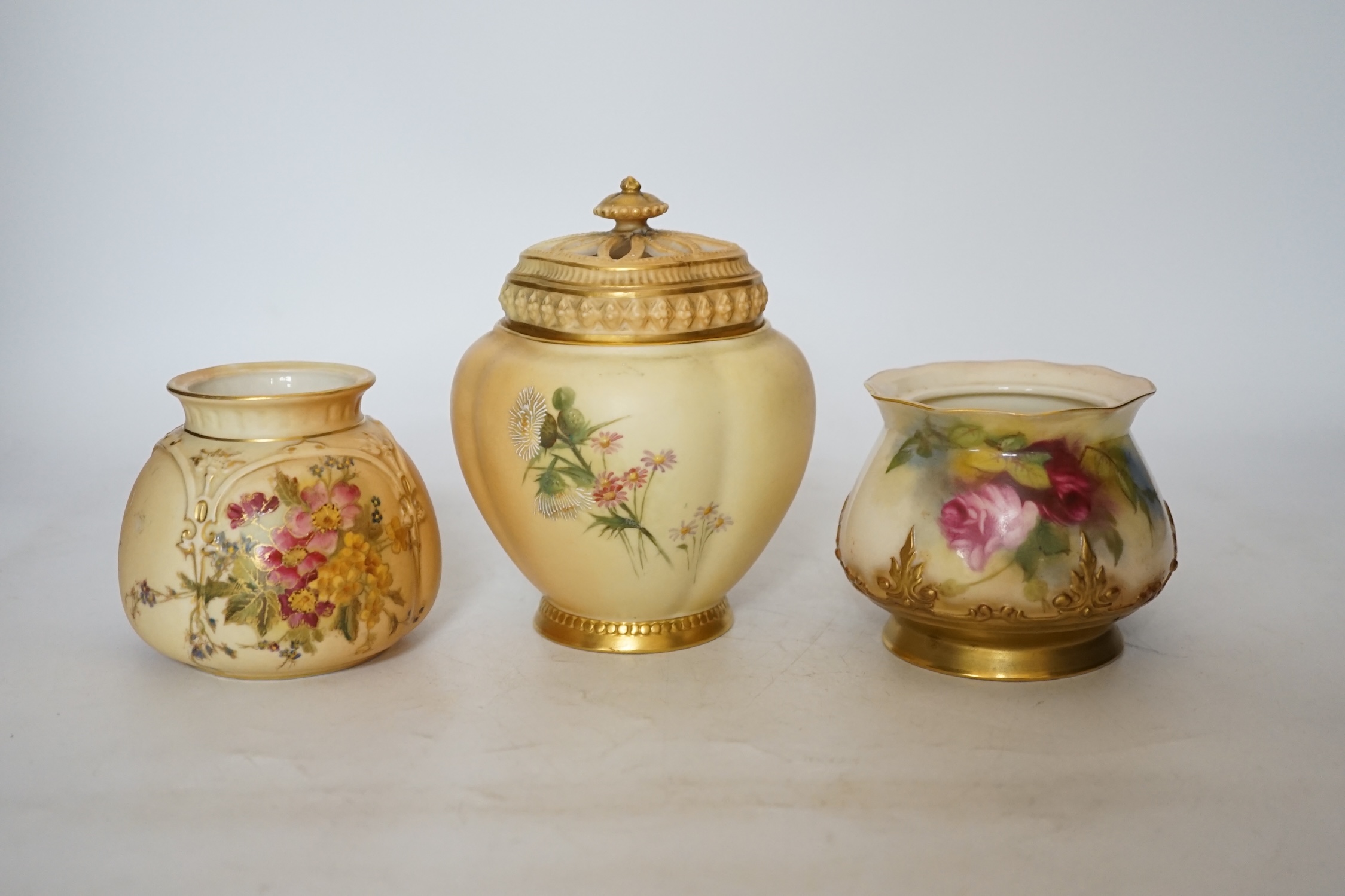 Three Royal Worcester blush ivory pots, one with an inner lid and pierced outer lid, tallest 14cm